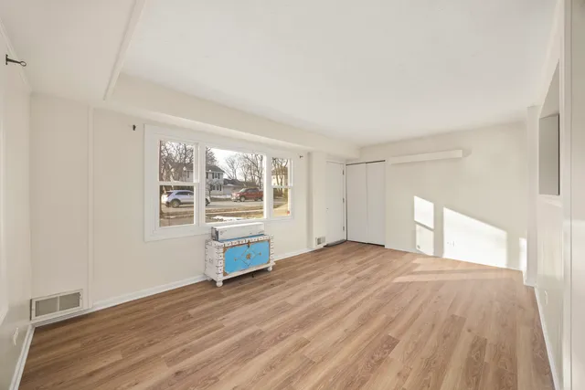 a view of an empty room with a window and wooden floor