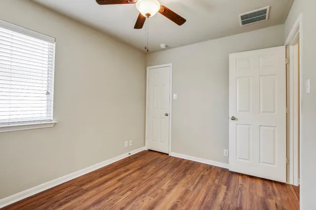 a view of empty room with wooden floor and fan