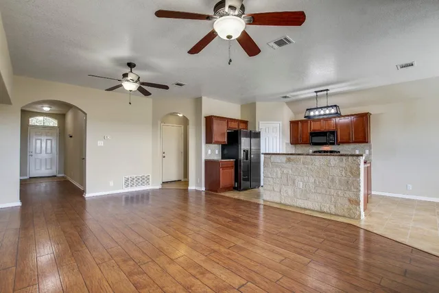 wooden floor in an empty room with a window and a kitchen