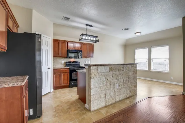 a kitchen with stainless steel appliances granite countertop a refrigerator a stove top oven a sink and dishwasher