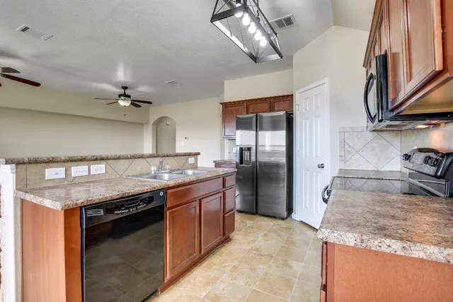 a kitchen with stainless steel appliances granite countertop a sink a stove and a refrigerator