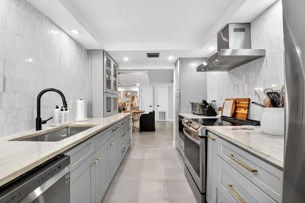 a large kitchen with stainless steel appliances granite countertop a sink and cabinets