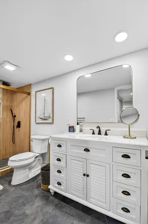 a bathroom with a double vanity sink a toilet a mirror and