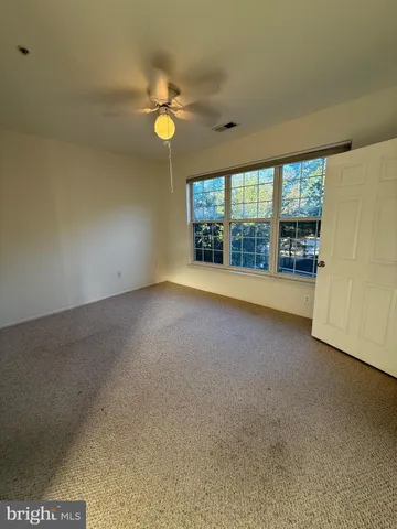 an empty room with chandelier fan and windows