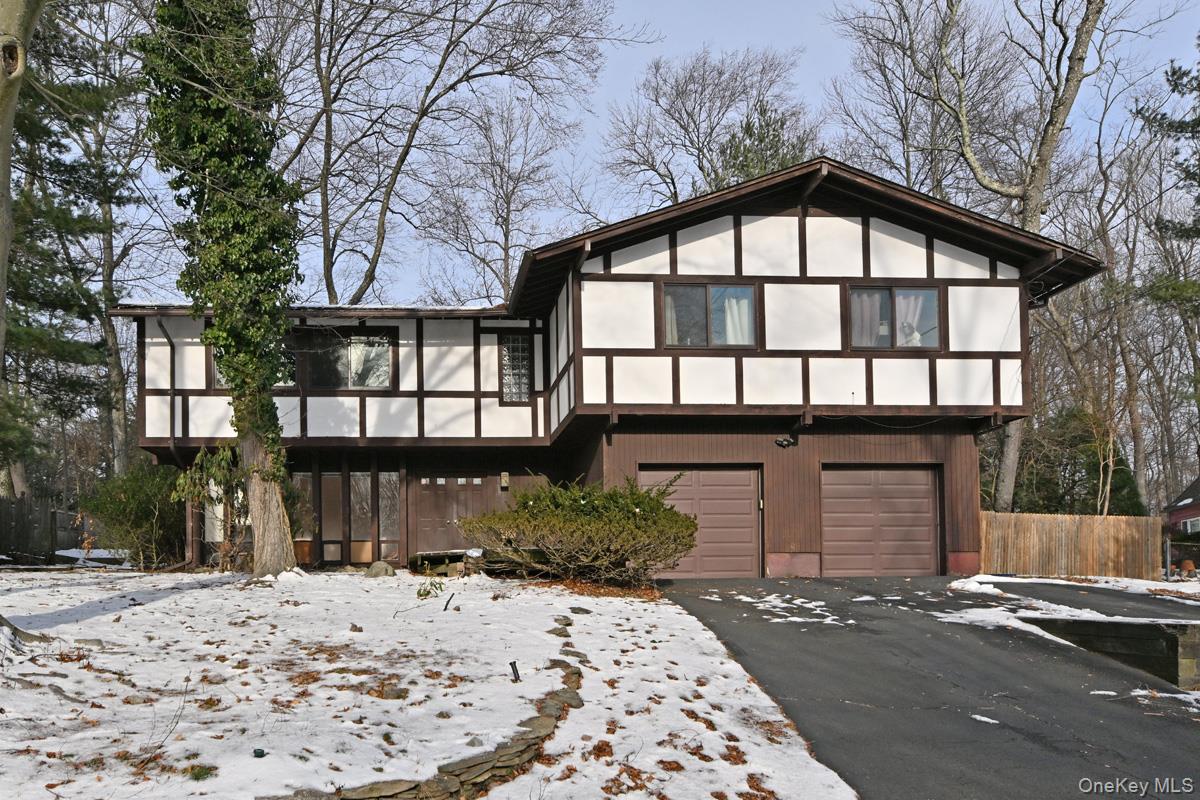 View of front of property featuring a sunroom, driveway, and an attached garage