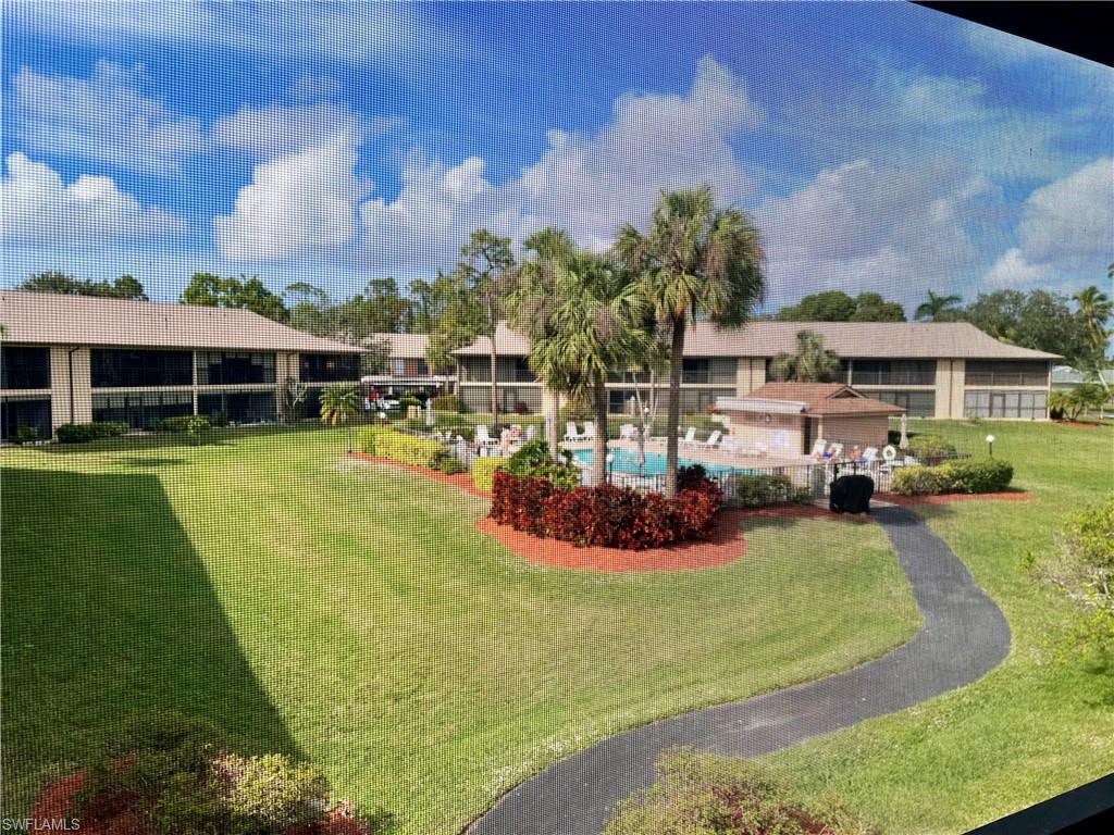 256 Pebble Beach Circle, Unit D201 Naples, FL 34113 - Photo 19 of 19 a view of a white house with a yard and sitting area