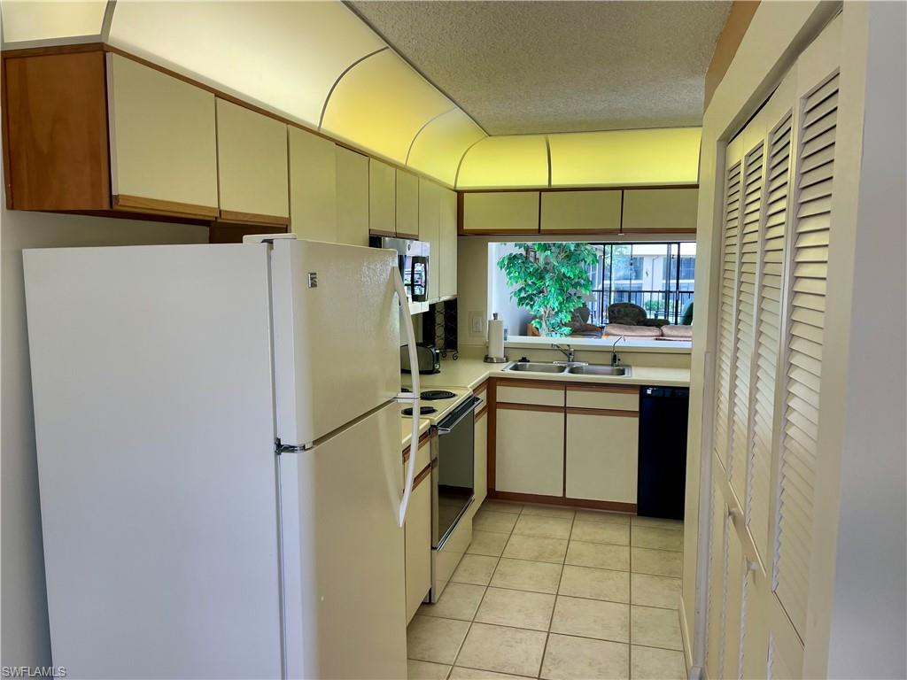256 Pebble Beach Circle, Unit D201 Naples, FL 34113 - Photo 4 of 19 a kitchen with stainless steel appliances a refrigerator sink and cabinets