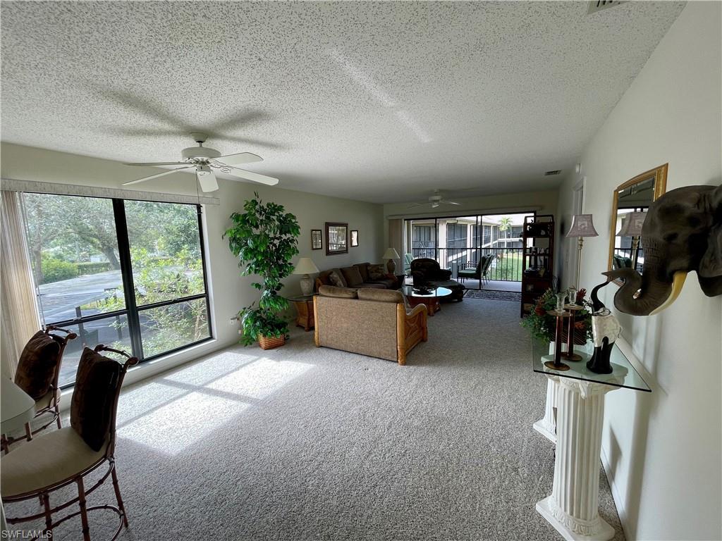 256 Pebble Beach Circle, Unit D201 Naples, FL 34113 - Photo 6 of 19 a living room with furniture a large window and gym equipment