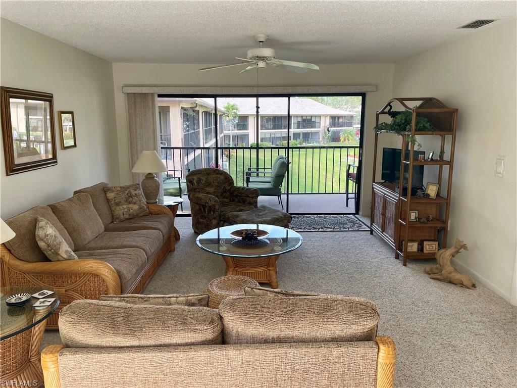 256 Pebble Beach Circle, Unit D201 Naples, FL 34113 - Photo 8 of 19 a living room with furniture and a floor to ceiling window