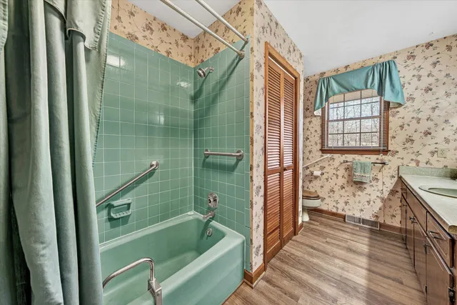 a view of an empty room with wooden floor and a ceiling fan
