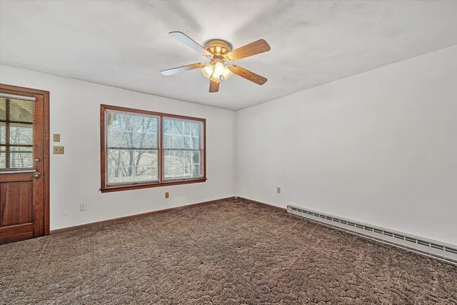 a view of a livingroom with a fireplace a ceiling fan and wooden floor