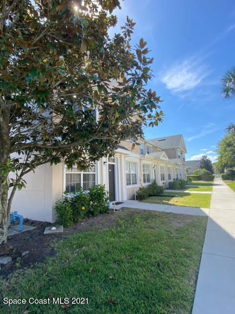 105 Turpial Way, Unit 105 Melbourne, FL 32901 - Photo 2 of 25 a view of a house with a big yard and palm trees
