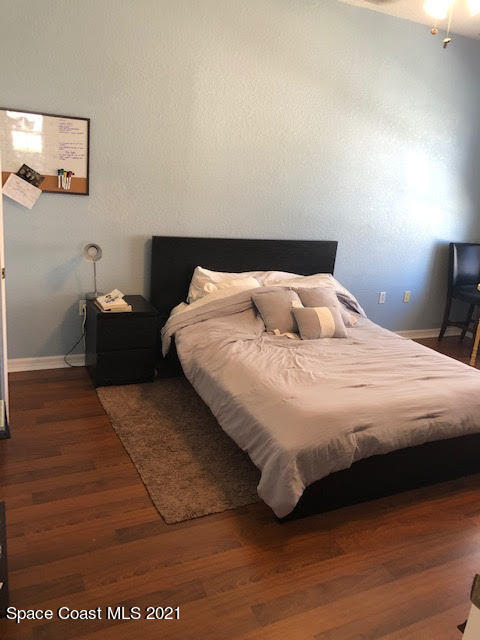105 Turpial Way, Unit 105 Melbourne, FL 32901 - Photo 11 of 25 a bedroom with a bed and wooden floor