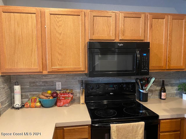 105 Turpial Way, Unit 105 Melbourne, FL 32901 - Photo 8 of 25 a kitchen with granite countertop a stove and a microwave