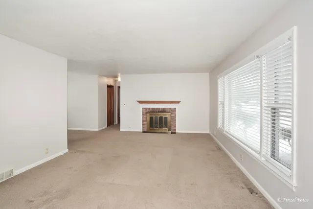a view of an empty room with a window and a fireplace