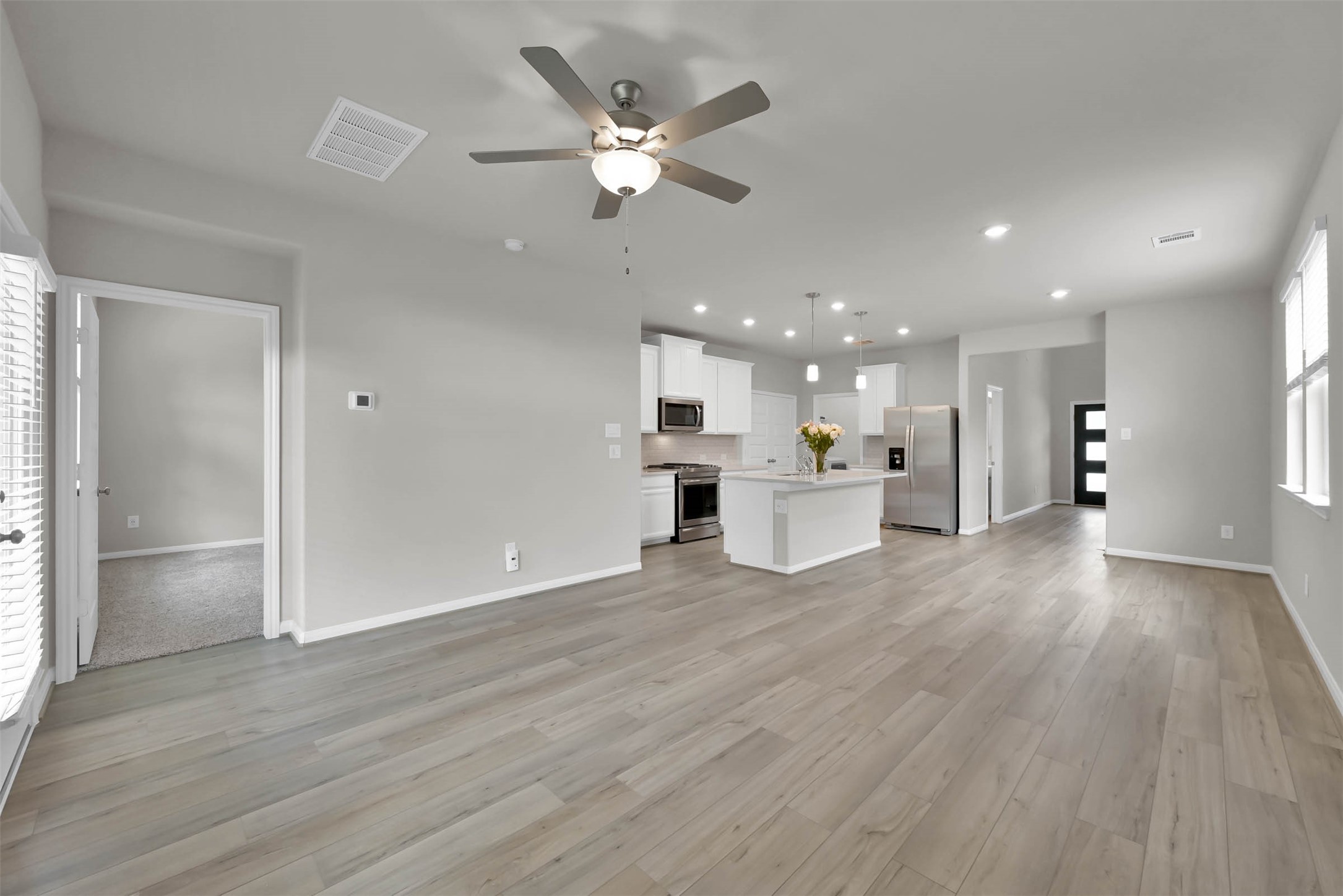 213 Harper Ridge Drive Montgomery, TX 77316 - Photo 12 of 34 a view of a kitchen with a kitchen island wooden floor cabinetry and a ceiling fan