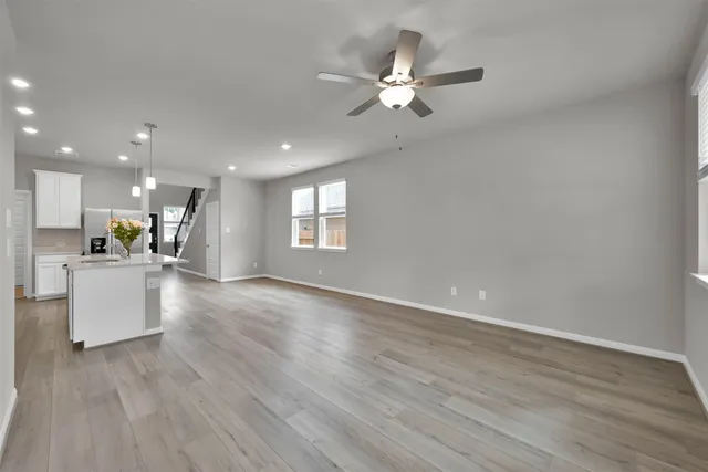 a view of an empty room with kitchen and window