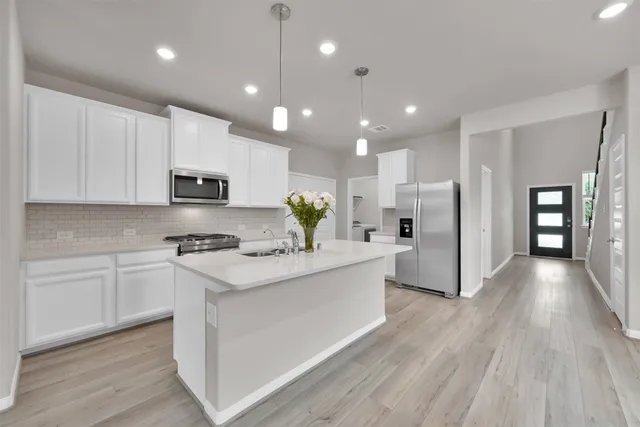 a kitchen with stainless steel appliances kitchen island granite countertop a stove a refrigerator a sink dishwasher and a microwave with wooden floor