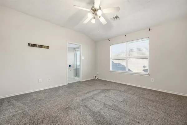 an empty room with chandelier fan and windows
