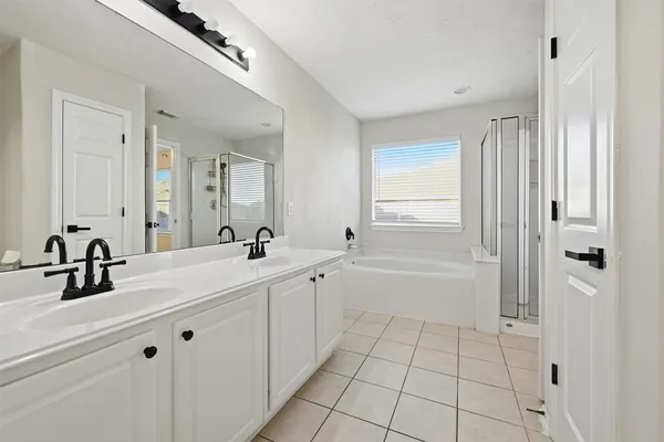 a bathroom with a double vanity sink a mirror and a bathtub