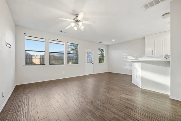 a view of an empty room with a window and wooden floor