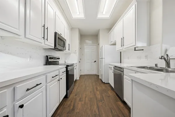 a kitchen with stainless steel appliances granite countertop a stove a sink dishwasher and a refrigerator with wooden cabinets