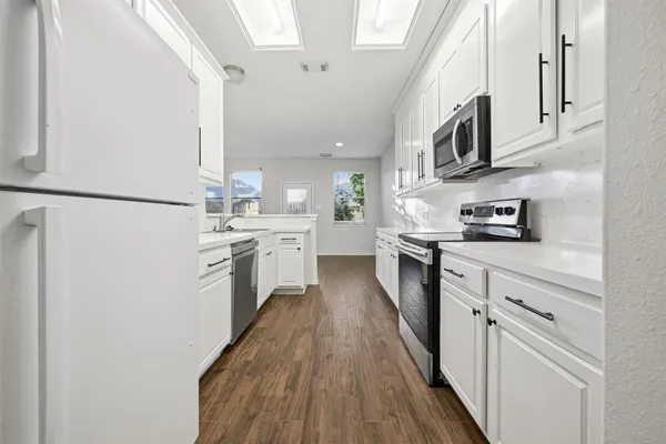 a kitchen with stainless steel appliances a refrigerator sink and white cabinets