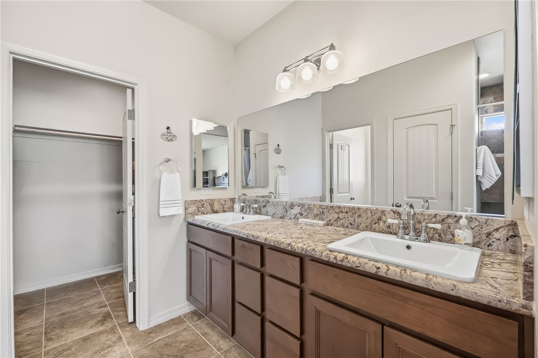 10809 North Jemez Road Kingman, AZ 86401 - Photo 11 of 51 Double vanity featuring granite-look countertops, integrated sinks, and wood-finish cabinetry