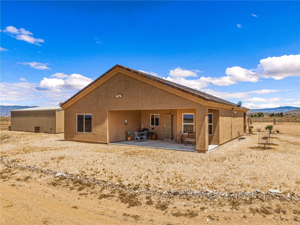 10809 North Jemez Road Kingman, AZ 86401 - Photo 13 of 51 Stucco exterior property featuring a covered patio, multiple windows, and a detached corrugated metal outbuilding
