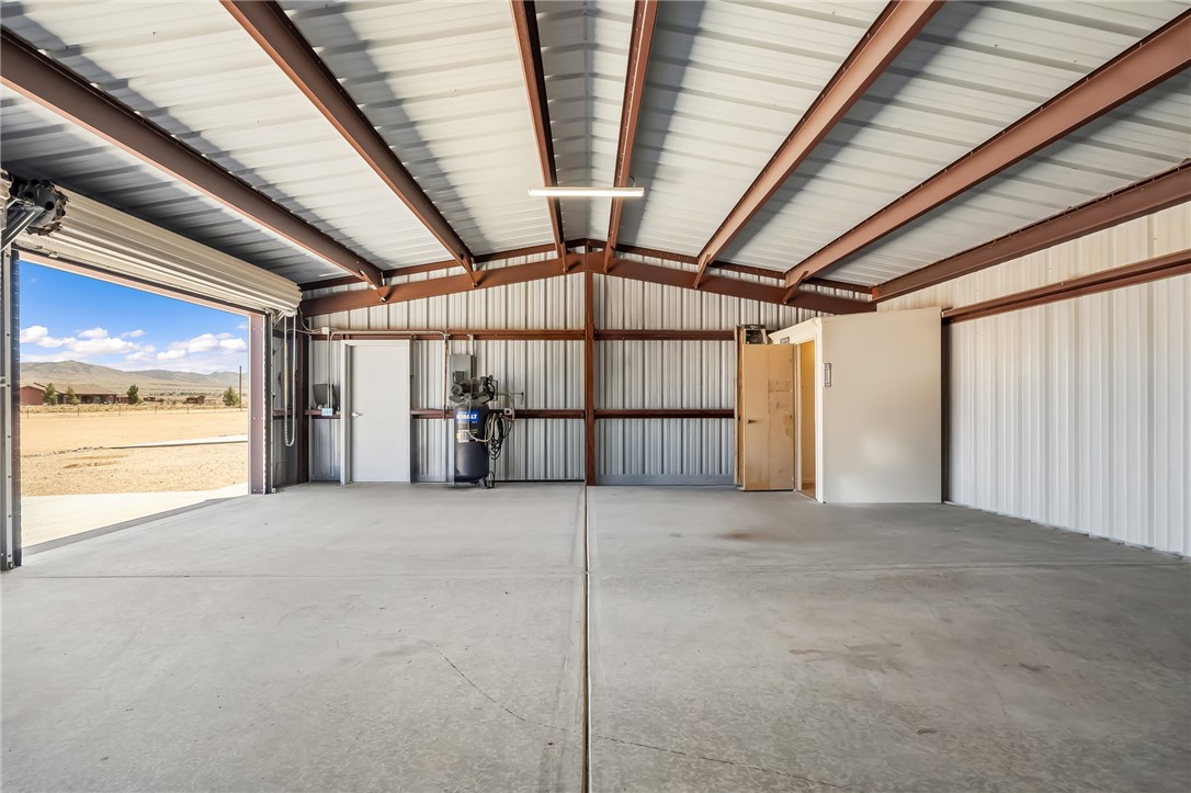 10809 North Jemez Road Kingman, AZ 86401 - Photo 16 of 51 Spacious metal building featuring a large roll-up door, exposed steel beam construction, corrugated metal walls, concrete flooring, and interior access door
