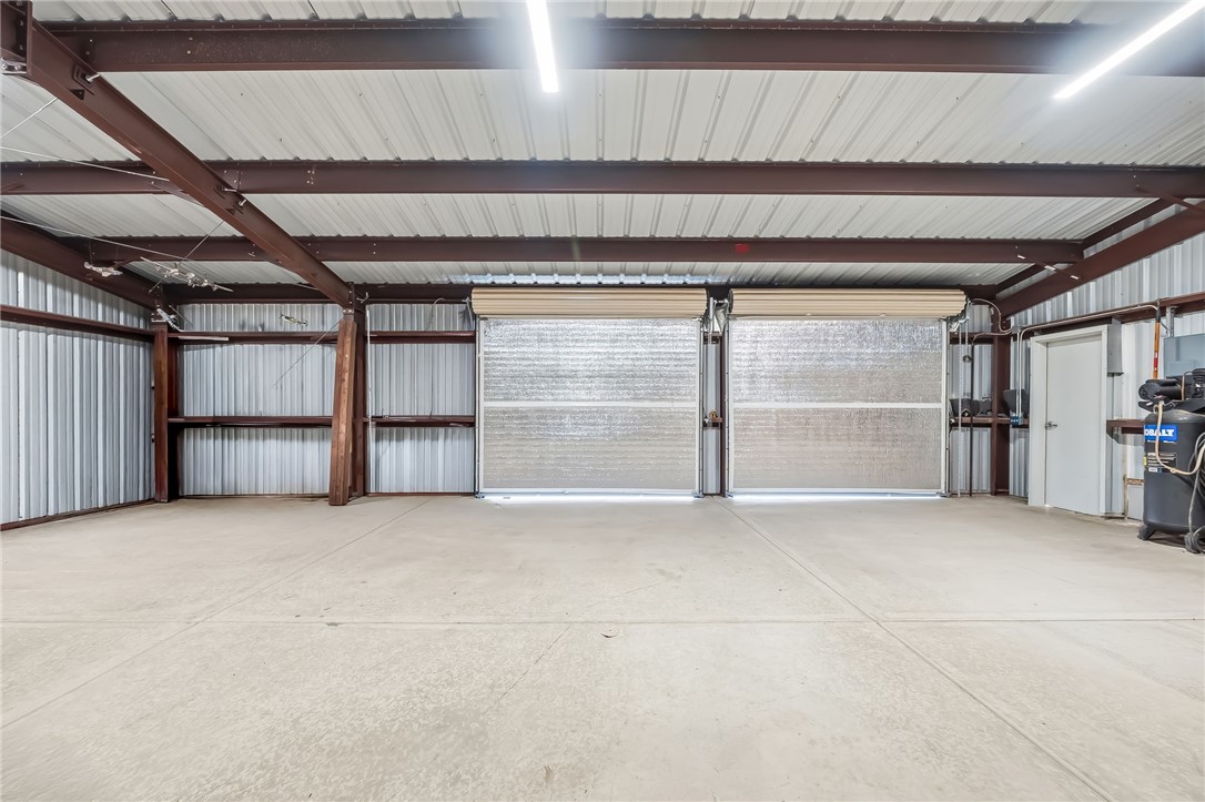 10809 North Jemez Road Kingman, AZ 86401 - Photo 17 of 51 Spacious interior featuring two roll-up doors, a concrete floor, exposed structural beams, and corrugated metal walls