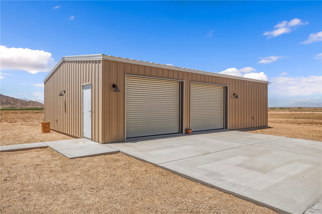10809 North Jemez Road Kingman, AZ 86401 - Photo 18 of 51 Corrugated metal structure featuring two roll-up garage doors, a pedestrian entry, and exterior wall-mounted lighting