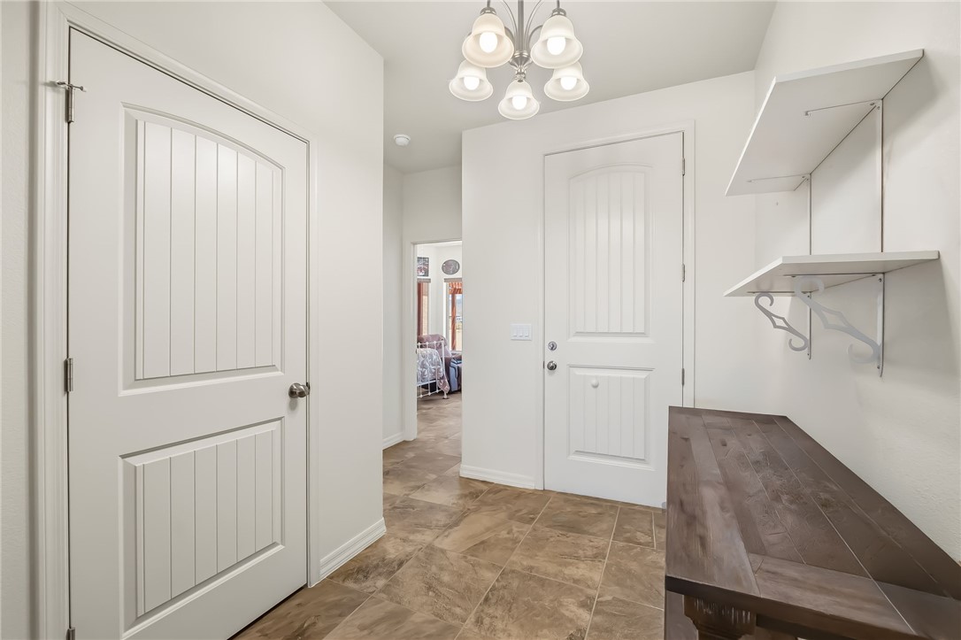 10809 North Jemez Road Kingman, AZ 86401 - Photo 22 of 51 Hallway featuring tile flooring, a decorative chandelier, white paneled doors, and built-in shelving