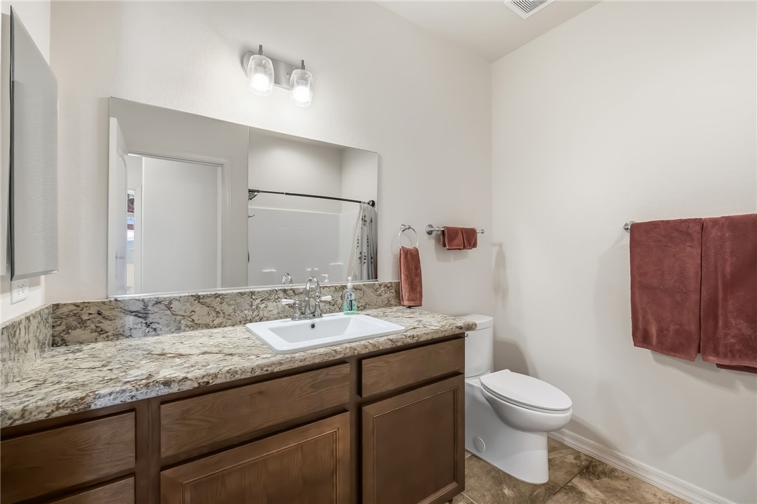 10809 North Jemez Road Kingman, AZ 86401 - Photo 27 of 51 Bathroom vanity featuring an integrated rectangular sink, granite-style countertop, and a wood-finish cabinet with ample storage