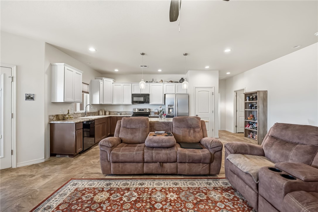 10809 North Jemez Road Kingman, AZ 86401 - Photo 33 of 51 Open-concept living space with tile flooring throughout, featuring a kitchen with white upper cabinetry, dark lower cabinetry, and granite-look countertops