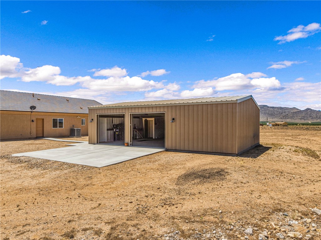 10809 North Jemez Road Kingman, AZ 86401 - Photo 4 of 51 Two-bay metal 30x40 structure with a concrete pad, featuring exterior lighting fixtures and a corrugated metal roof