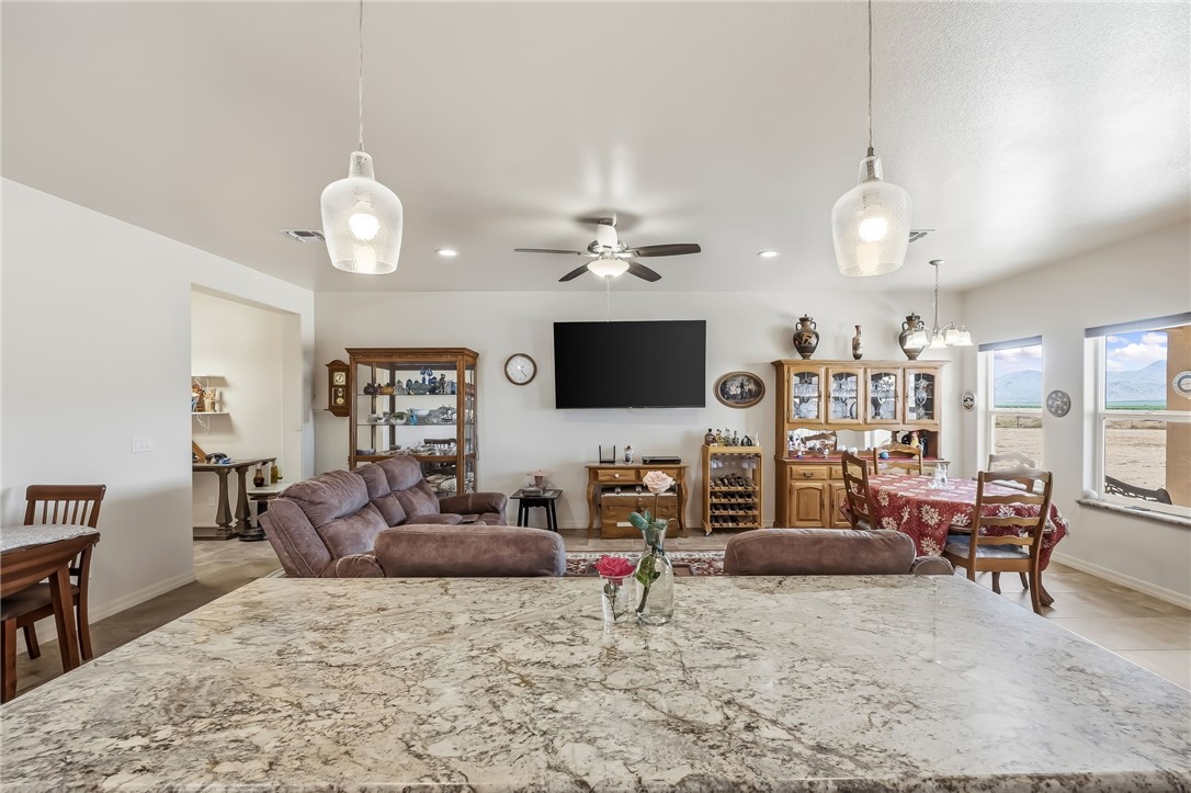 10809 North Jemez Road Kingman, AZ 86401 - Photo 5 of 51 Spacious open-concept living area featuring a large stone-finish countertop, two clear glass pendant lights, a ceiling fan, and multiple windows offering expansive outdoor scenery