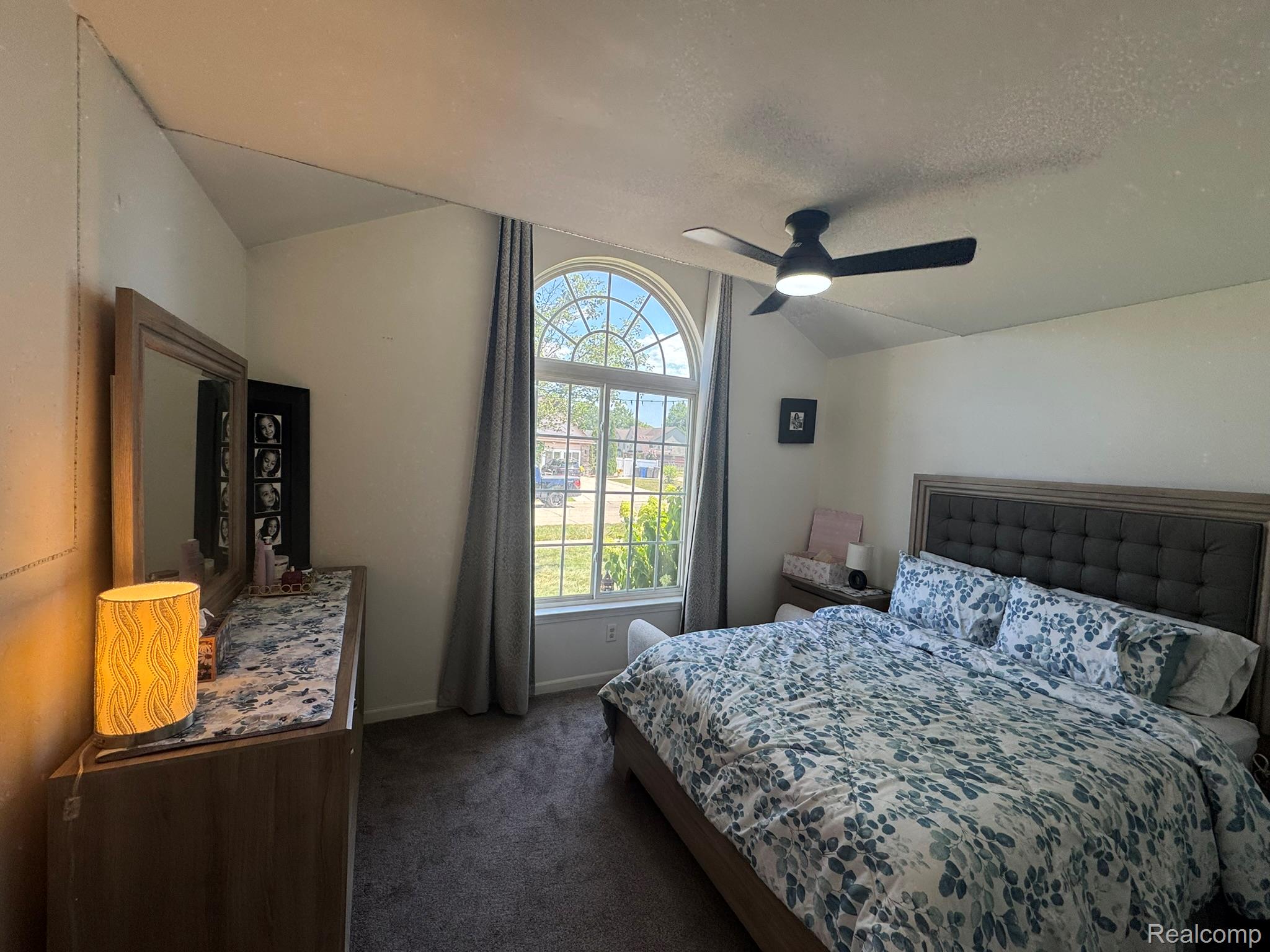 324 Cherry Lane Inkster, MI 48141 - Photo 22 of 28 Arched window with detailed grilles, ceiling fan with integrated lighting, tufted headboard, and wood-finish dresser with mirror
