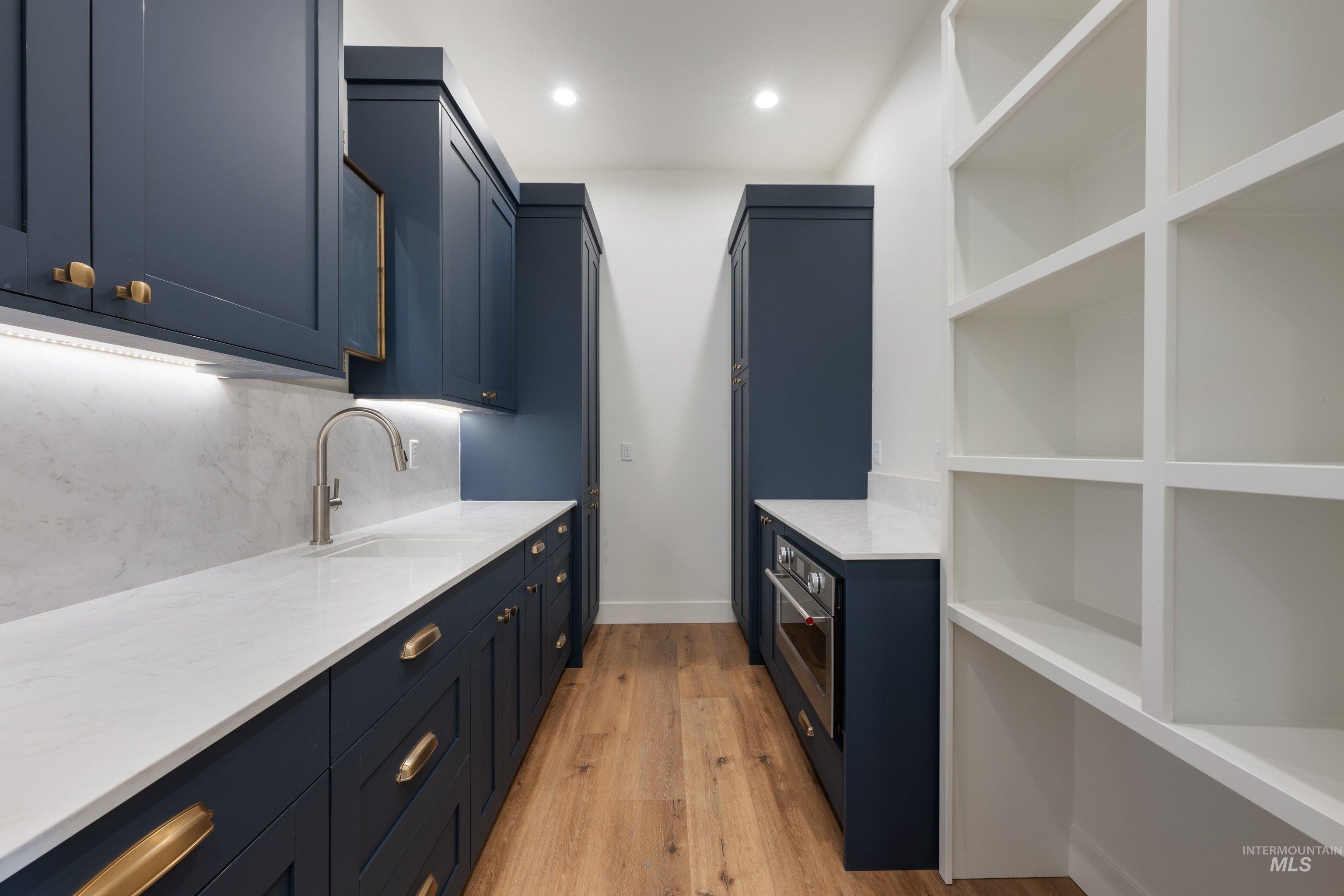 24821 Ardmore Court Caldwell, ID 83607 - Photo 23 of 43 Galley-style pantry featuring ample custom cabinetry, stone countertops, wood-finish flooring, a built-in oven, and open shelving