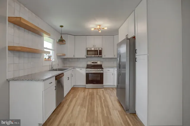 a kitchen with granite countertop a sink stove oven and refrigerator