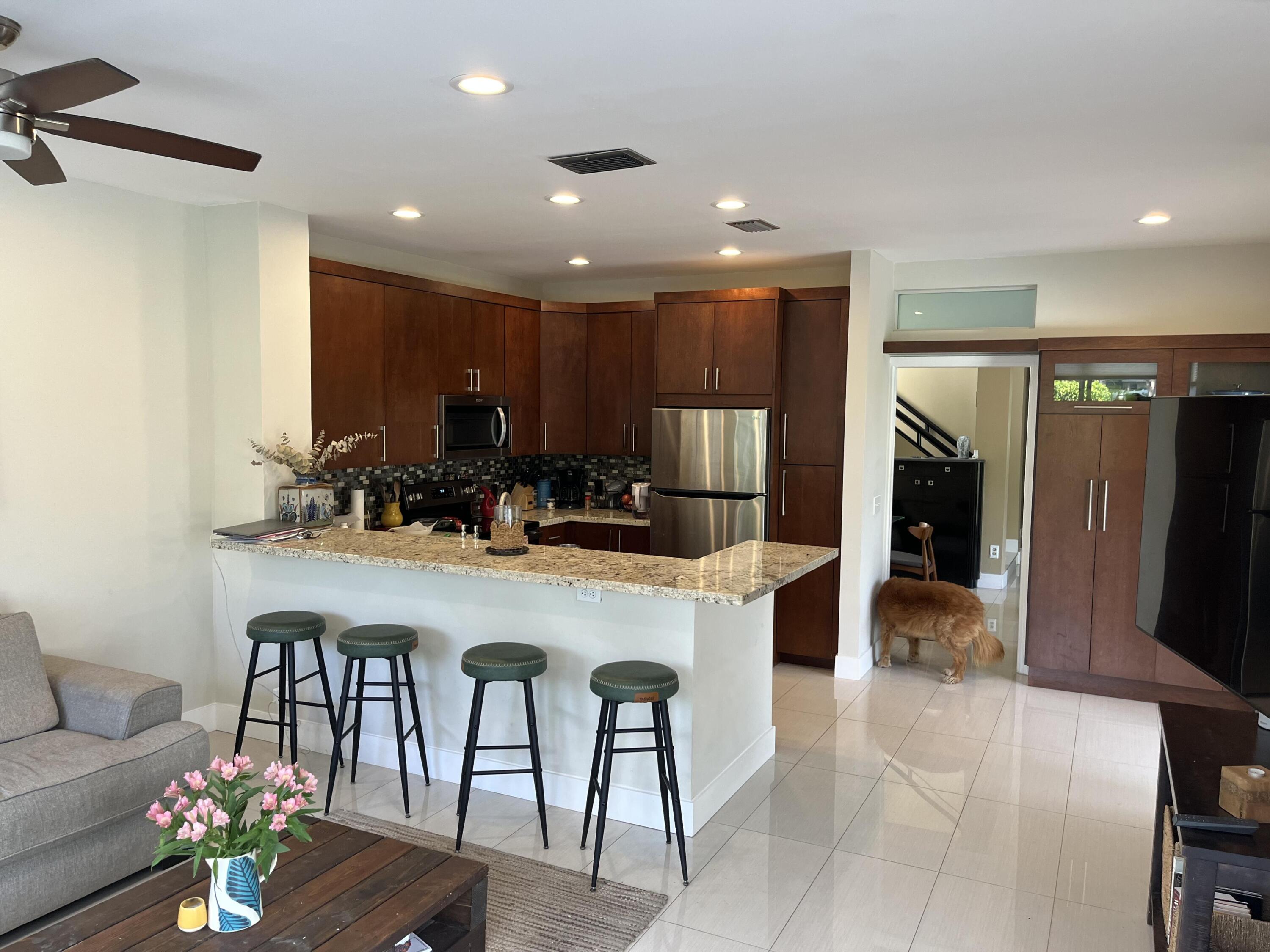 17651 Tiffany Trace Drive Boca Raton, FL 33487 - Photo 5 of 17 a kitchen with stainless steel appliances kitchen island granite countertop a refrigerator a stove and a dining table with wooden floor