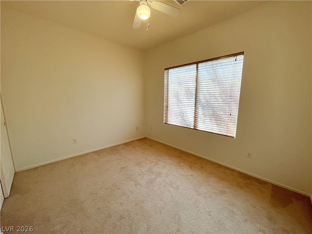 691 Principle Point Avenue Henderson, NV 89012 - Photo 25 of 30 A well-lit bedroom features plush carpeting and a ceiling fan for optimal comfort.