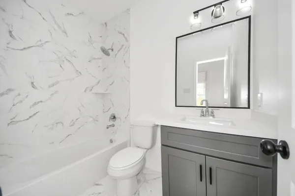 a bathroom with a granite countertop sink a toilet mirror and bathtub