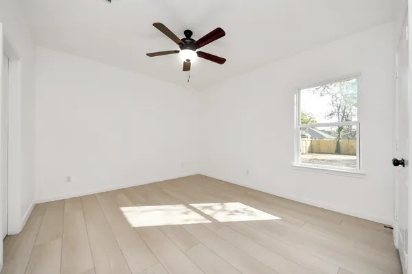 an empty room with wooden floor and windows