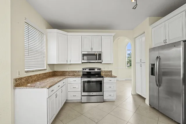 a kitchen with granite countertop white cabinets and stainless steel appliances