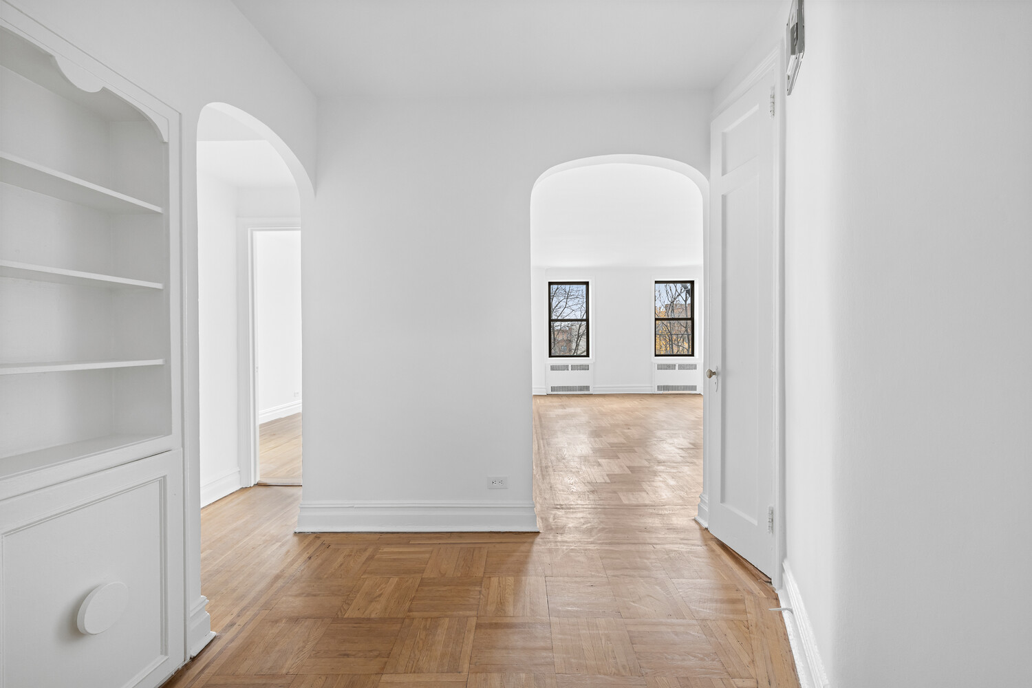 a view of an empty room with cabinet and a window