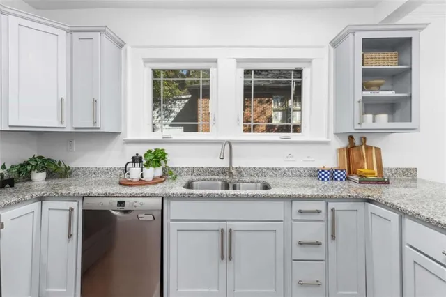 a kitchen with stainless steel appliances granite countertop white cabinets and a window