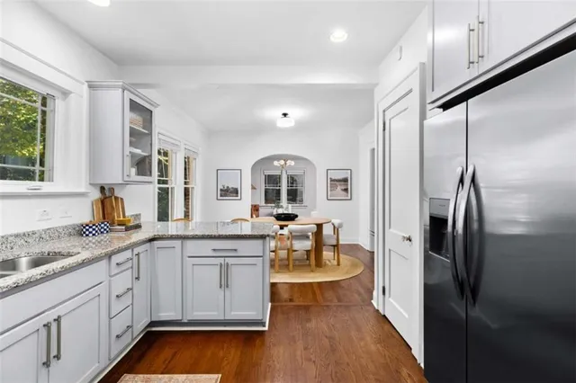 a open kitchen with stainless steel appliances granite countertop a refrigerator a sink dishwasher a stove and white cabinets with wooden floor