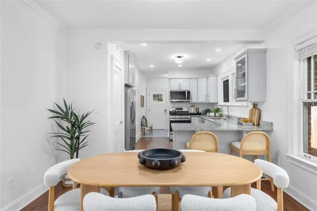 a kitchen with granite countertop a white refrigerator a stove a dining table and chairs