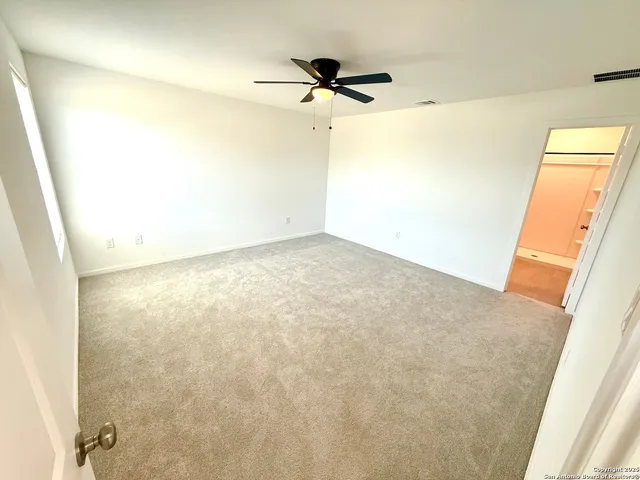 an empty room with a window and a ceiling fan